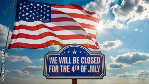 American flag waves proudly above a Fourth of July closing sign set against a bright sunny sky