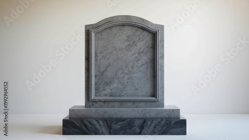 Blank grey marble tombstone with a classic arched design stands against a simple light background