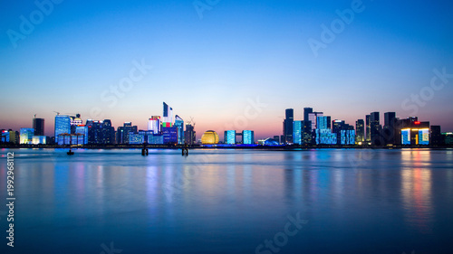 Tableau sur toile Hangzhou Qianjiang New Town skyline at dusk over calm river