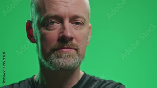 Confident man looking up then turning to camera on green screen background.
