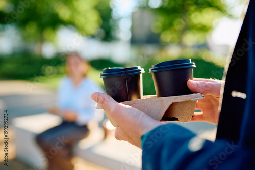 Konstfotografi Person carrying two takeaway coffee cups in a holder, delivering drinks to a col