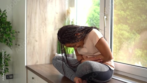 African american teenage girl suffering from stomach ache at home