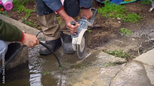 Construction workers cutting a concrete slab with a circular diamond saw
