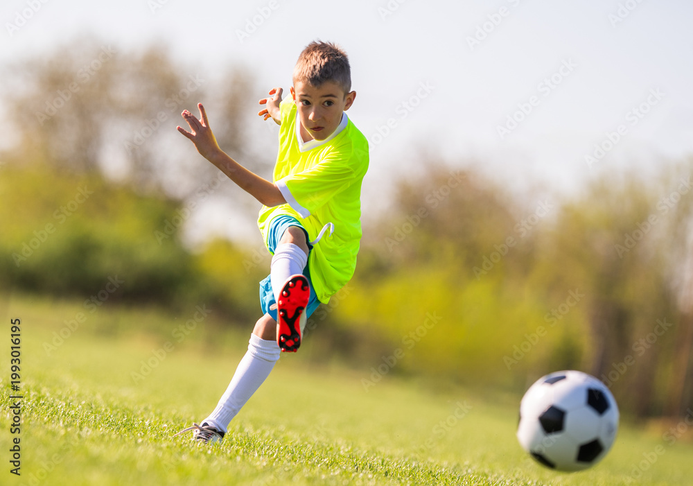 Fototapeta premium Young boy kicking soccer ball