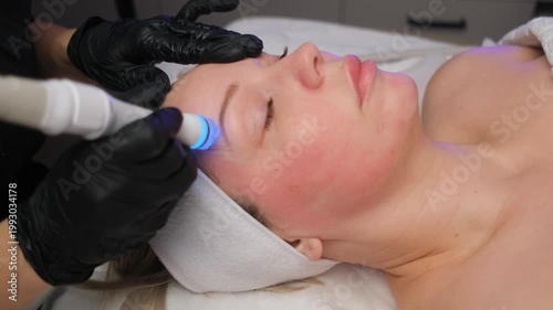 Professional cosmetologist performing a rejuvenating aquapilling procedure on a female client's face with modern equipment in a spa clinic