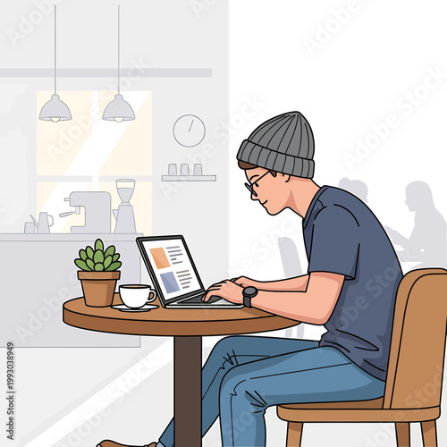 A man in casual clothing works on a laptop at a small table in a modern coffee shop with a plant and coffee cup.