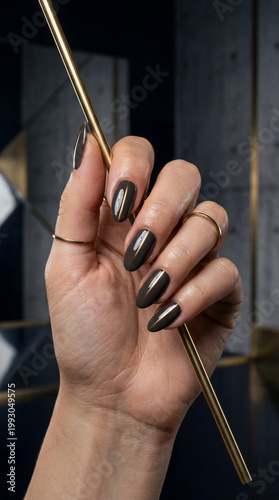 Elegant woman hand with Tuscan nails 2000 style featuring dark brown polish and gold line detail for art deco aesthetic and glamour luxury manicure inspiration