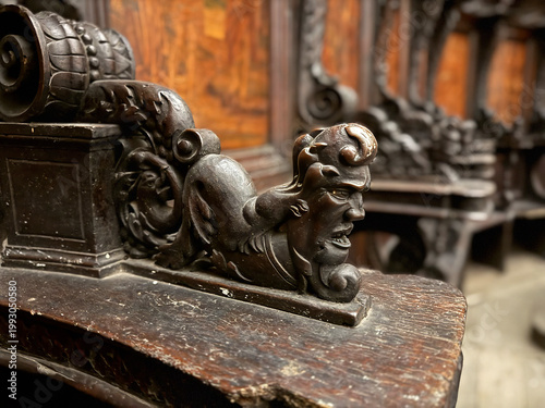 Photos CAPUA, ITALY - NOV 2025: Close-up of a wood-carved armrest in the choir stalls at the Church of Saint Mary of the Announcement, featuring a putto riding a mythical creature