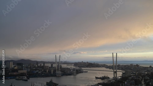 Timelapse city harbor at dusk with dramatic cloudscape and bridge silhouettes.