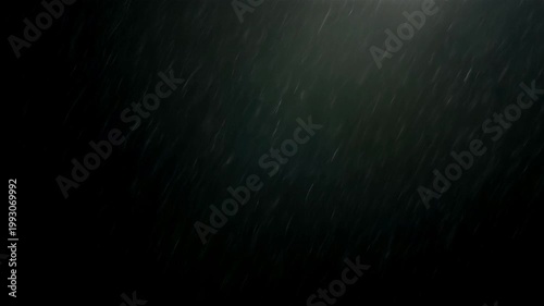 Heavy rain falling against a dark black background at night with dramatic atmospheric lighting effects