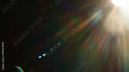 Golden lens flare with rainbow light points on a dark background for cinematic video overlays