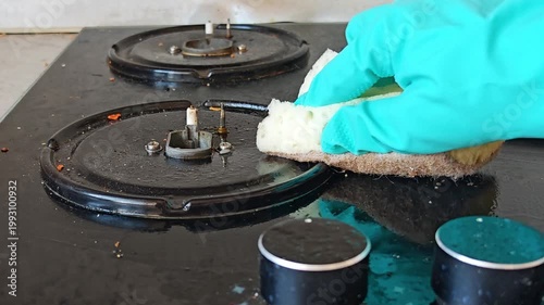 Hand wiping the surface of a gas stove with a cloth. kitchen cleaning, spotless home, household routine.