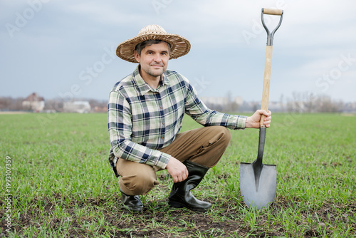 Obraz na płótnie Farmer kneeling with shovel in spring field, soil preparation agribusiness conce