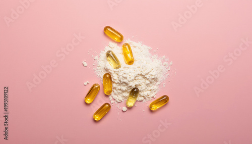 Yellow omega 3 fish oil softgels and white collagen powder on a pink background for health and wellness