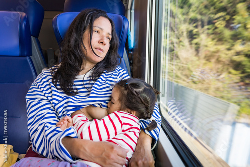 mother and daughter travel together by train as a family, beastfeeding in public
