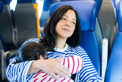 mother and daughter travel together by train as a family, beastfeeding in public
