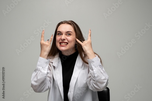 Quadro su tela Young woman making rock and roll hand gestures while grimacing, showing exciteme