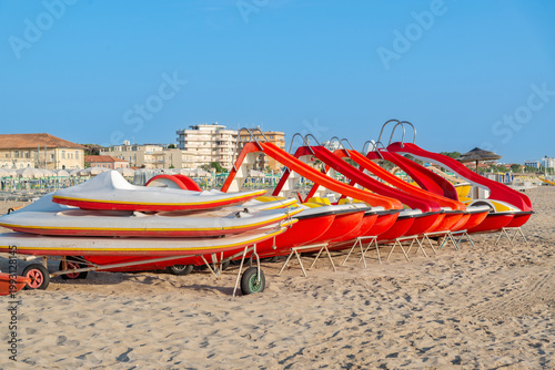Colorful water slides lined up on the sandy beach in a busy resort area during the summer