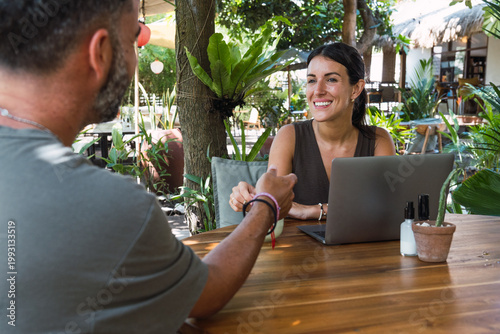 Woman and man having a conversation while working in an outdoor cafe