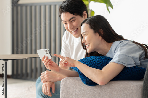 Принти на полотні ソファでスマホを見る笑顔の夫婦