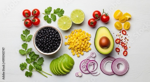 Fresh mexican food ingredients arranged on white wood surface with tomatoes black beans corn avocado lime red onion cilantro and red pepper flakes preparation.