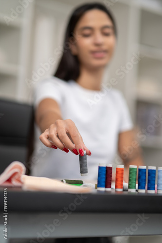 Female fashion designer working with fabric and colorful threads