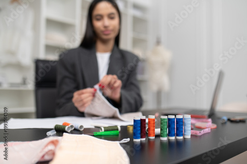 Female fashion designer working with fabric and colorful threads