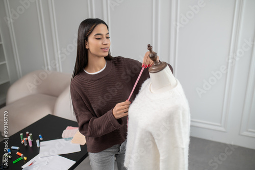 Photography Dark-haired young woman holding anew white jacket and smiling nicely