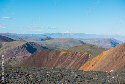 Scenic top view from sunlit stony plain to big colorful mountain range in bri...