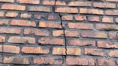 Camera moves upward along a long crack on a brick wall. Concept of structural damage, building defect, foundation problems and need for repair or inspection. 4K video.