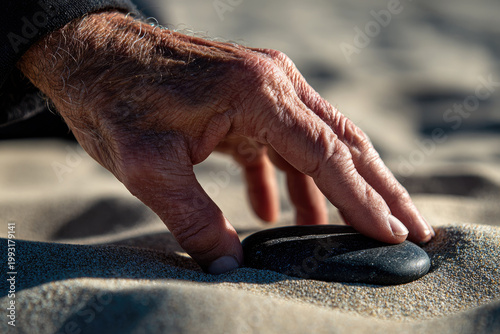 Zen garden meditation walk with peaceful hand gently touching smooth stone on soft sand creating tranquil atmosphere for mindfulness and relaxation outdoors