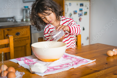 littl toddler girl baking at home in the kitchen with flour, concept activity with children, cooking together with complicity