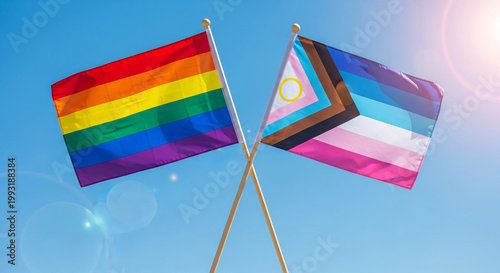 Two crossed flags against blue sky: rainbow flag and progress pride flag, representing inclusivity and support, ideal for tolerance and diversity concepts