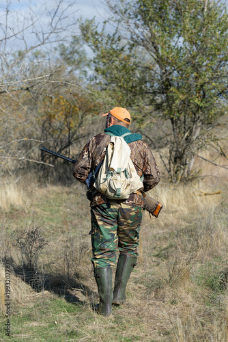 A hunter with a gun in camouflage clothing. A gentleman with a gun, medium shot, unrecognizable.