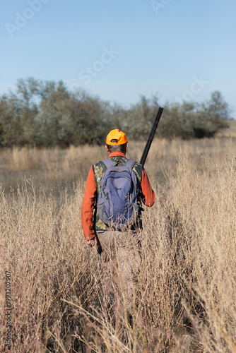 A hunter with a gun in camouflage clothing. A gentleman with a gun, medium shot, unrecognizable.