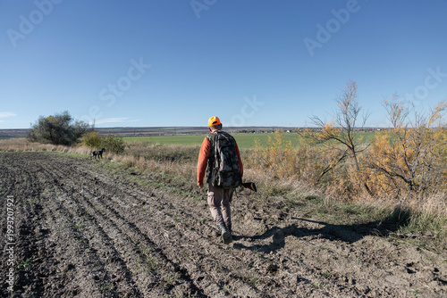 A hunter with a gun in camouflage clothing. A gentleman with a gun, medium shot, unrecognizable.