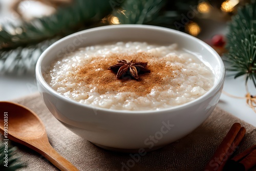 A Creamy White Bowl of Rice Porridge Topped with Cinnamon and Star Anise Served on a Wooden Surface with Festive Greenery and Twinkling Lights in the Background Perfect for a Cozy Winter Meal