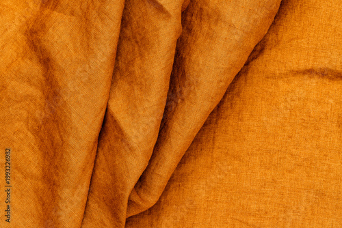 Textured orange fabric draped on a surface in natural light revealing its soft structure and warm tones