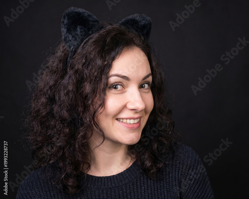 Attractive woman wearing cat ears on black background