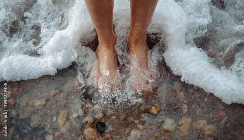 There is a person that is standing in the water with their feet in the water