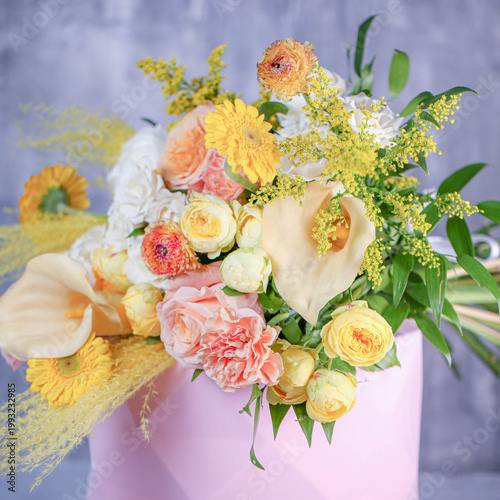 Fotografie Bright flowers in a pink vase on a plain background during daylight