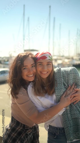 Affectionate mother and her teenage daughter enjoying a sunny day together at a marina