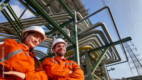 Fotografie Two Caucasian industrial engineers, a man and a woman wearing orange safety cove