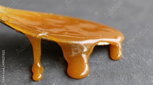 Golden Caramel Sauce Dripping Off A Spoon On Dark Background In A Cozy Kitchen Setting