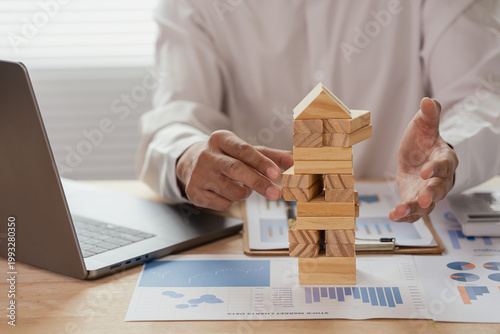 The image depicts a businessman building a tower from wooden blocks, illustrating the concept of business strategy and planning for success.