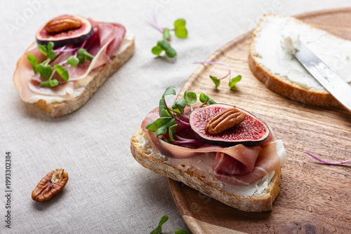 Bild auf Leinwand Slices of white bread with young cream cheese, meat, freshly sliced figs and radish sprouts