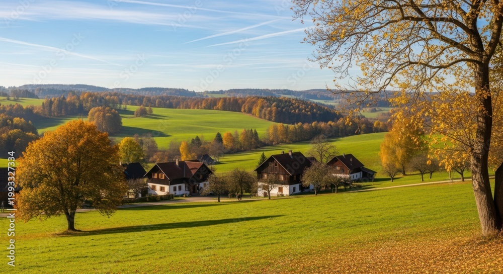 Fototapeta premium Charming European village nestled among rolling hills in vibrant autumn scenery with traditional homes under a clear blue sky.