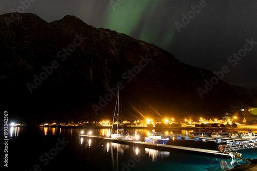 A bautiful aurora borealis display over boats in Norddal village harbor. A spectacular winter night scenery of Norway.
