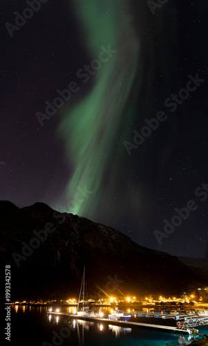 A bautiful aurora borealis display over boats in Norddal village harbor. A spectacular winter night scenery of Norway.