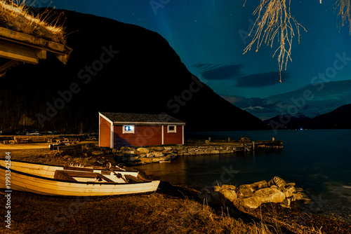 A bautiful aurora borealis display over boats in Norddal village harbor. A spectacular winter night scenery of Norway.